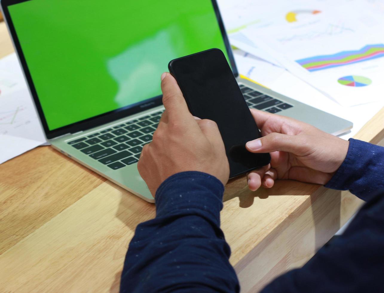 man met een telefoon in de buurt van een laptopmodel foto