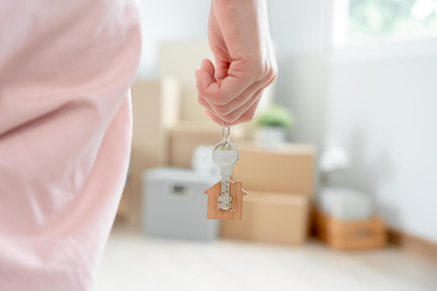 in beweging huis, verhuizing. vrouw houden sleutel huis sleutelhanger in nieuw appartement. Actie in nieuw huis. kopen of huur echt landgoed. vlak huur, erfpacht eigendom, nieuw landheer, onderkomen, lening, hypotheek. foto