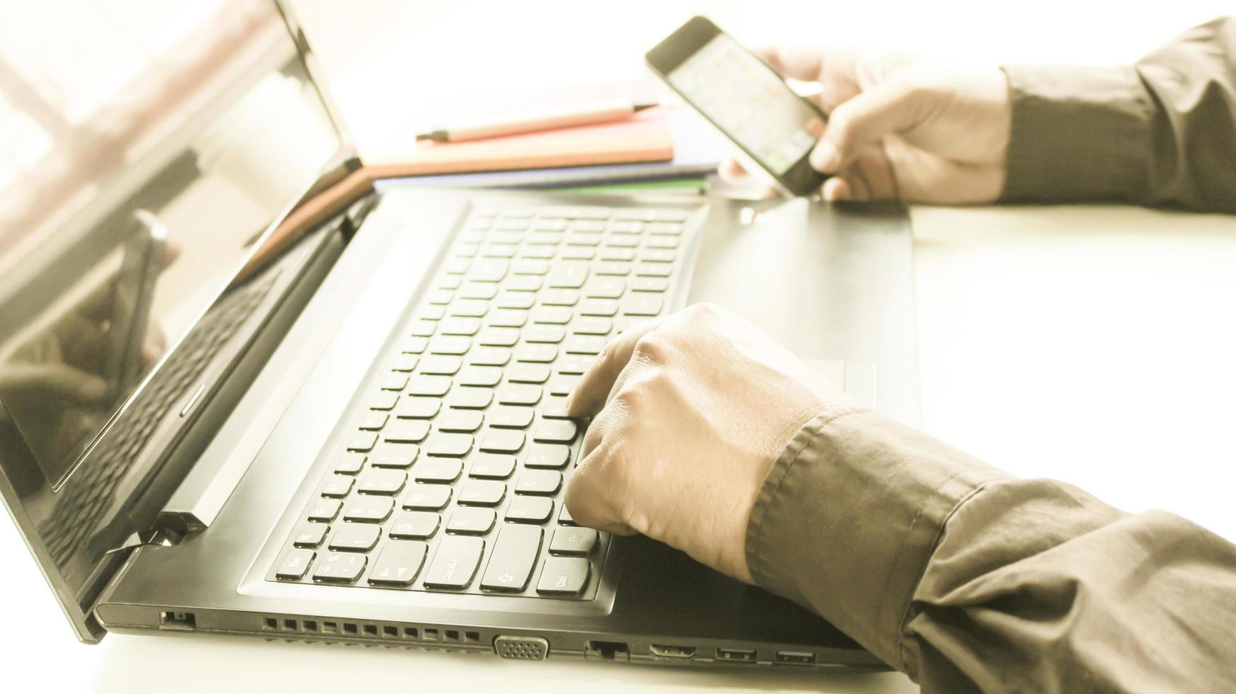 persoon die aan laptop en telefoon werkt foto