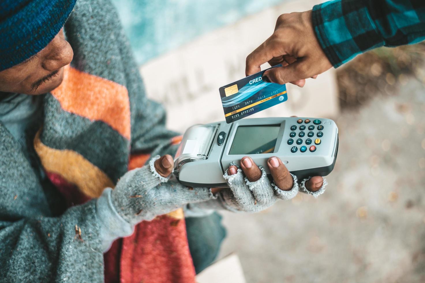 bedelaars die onder het viaduct zitten met een creditcard en een creditcard-veegmachine foto