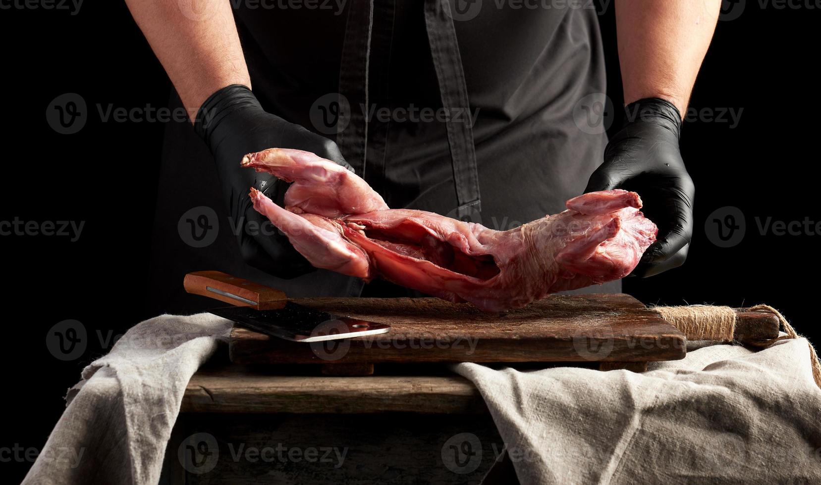 chef in zwart latex handschoenen houdt een geheel konijn karkas foto