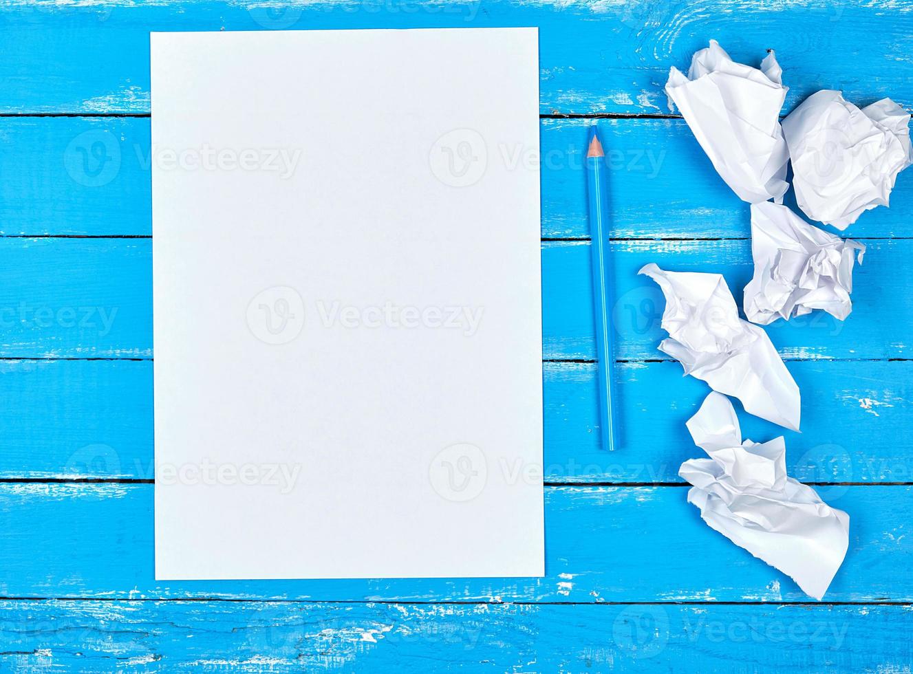 blanco wit rechthoekig vel van papier en verfrommeld stukken van papier Aan een blauw houten achtergrond foto