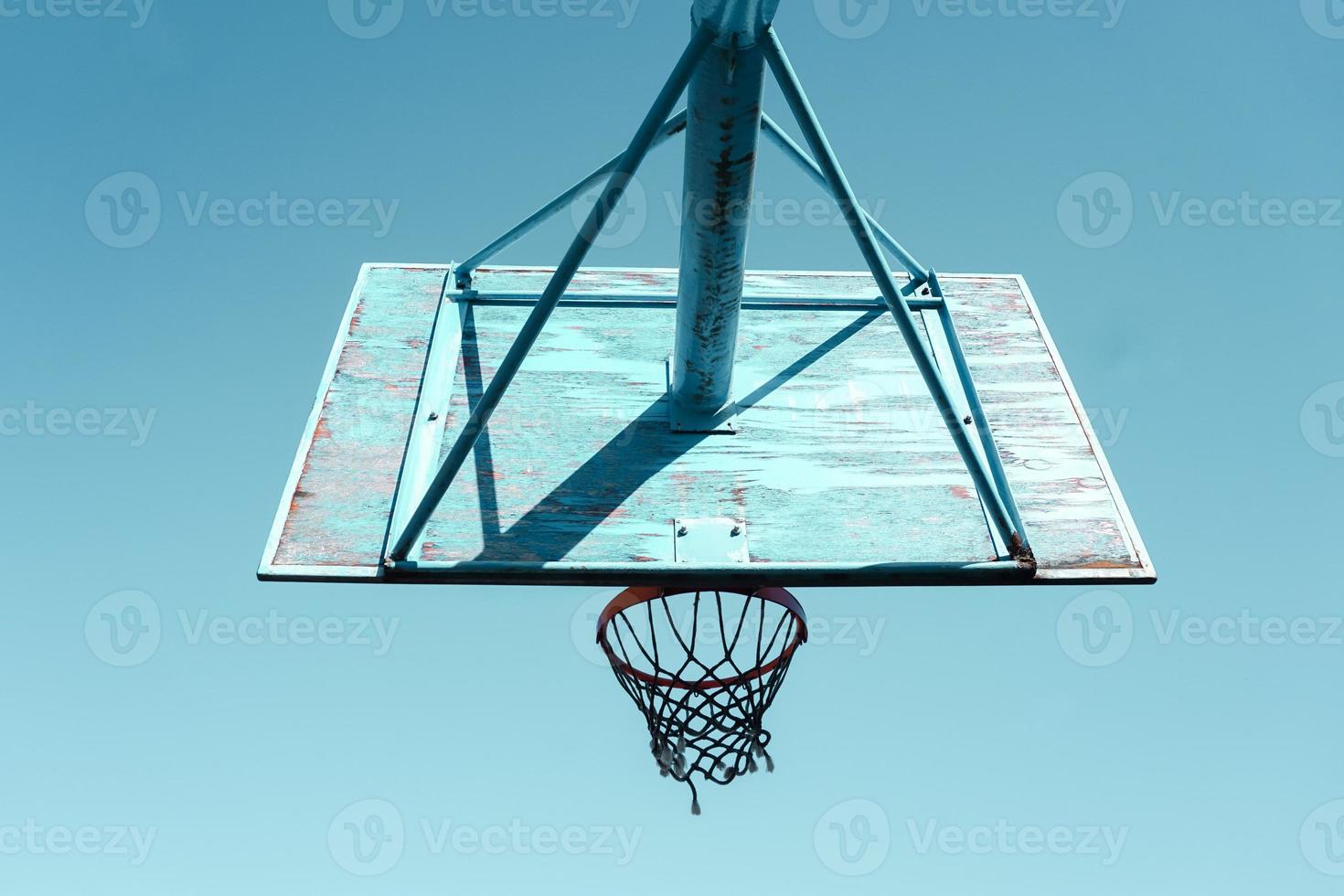 oud verlaten straat basketbal hoepel en blauw lucht achtergrond foto