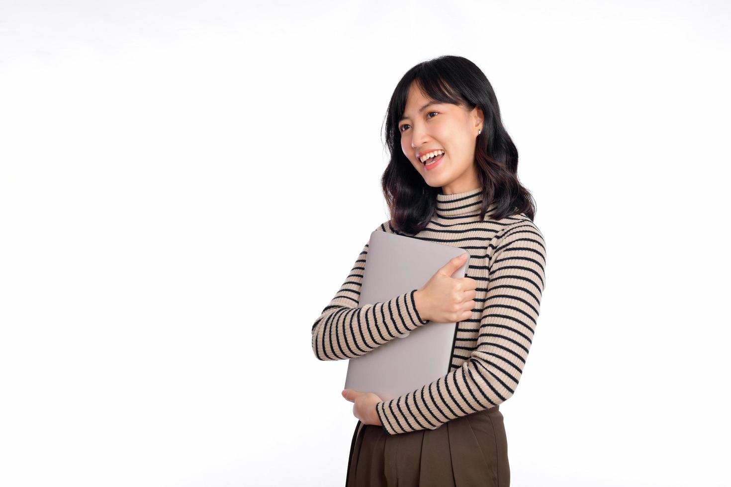 mooi jong Aziatisch vrouw Aan trui kleding Holding laptop pc computer en op zoek Bij camera met glimlach gezicht, geïsoleerd Aan wit achtergrond foto
