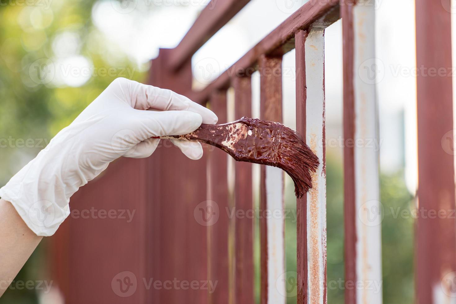 hand- houdt een penseel en verven de schutting, reparatie. foto