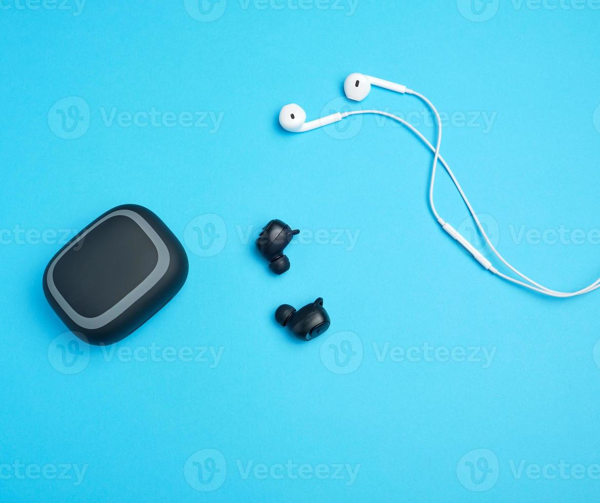 zwart draadloze en wit oortelefoons met draad Aan een blauw achtergrond foto