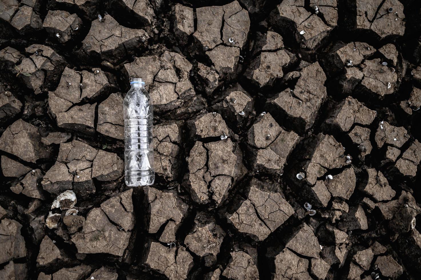 waterfles op droge grond met droog land foto