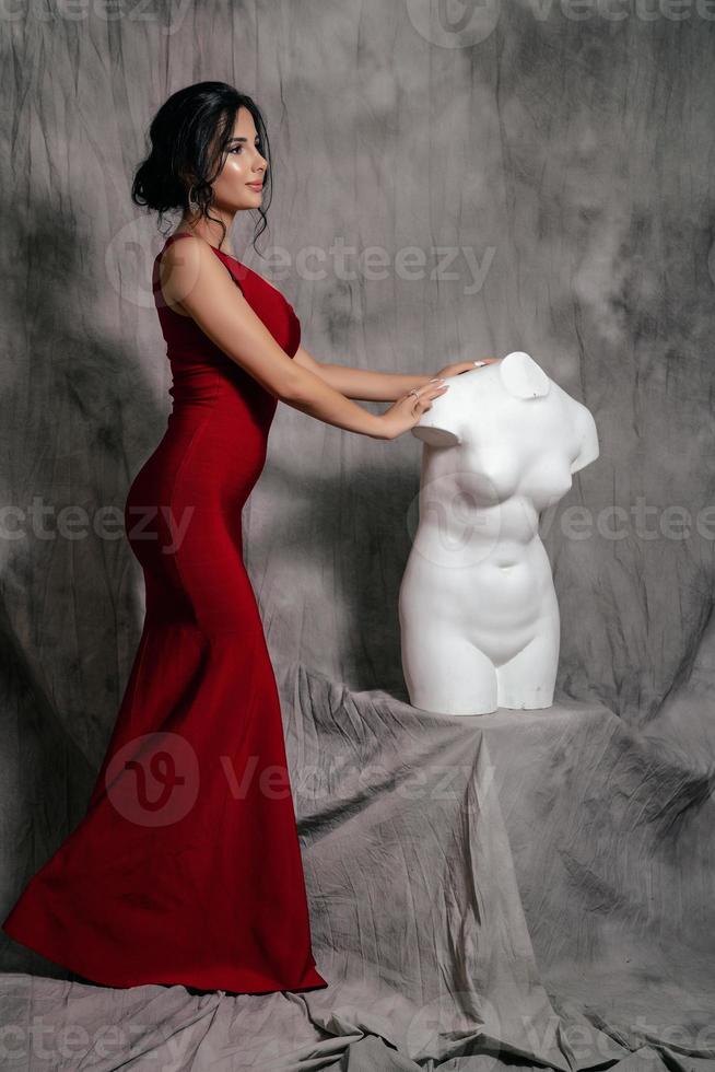 meisje in een rood avond jurk Aan een grijs achtergrond foto