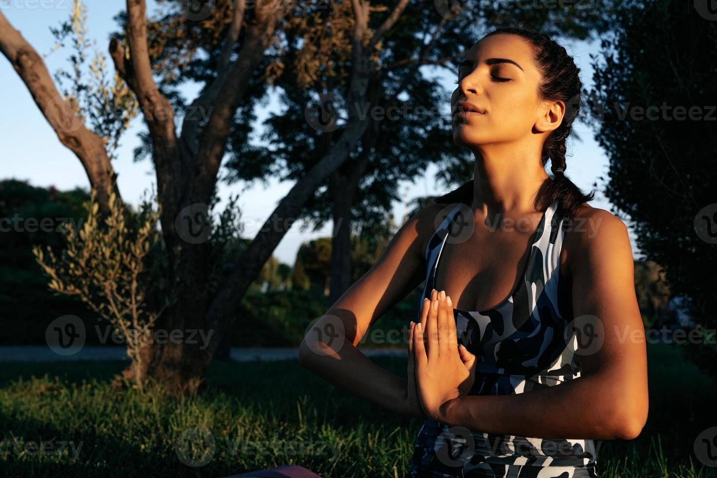 een meisje is verloofd in yoga in natuur Aan een fyloot mat Gesloten ogen foto