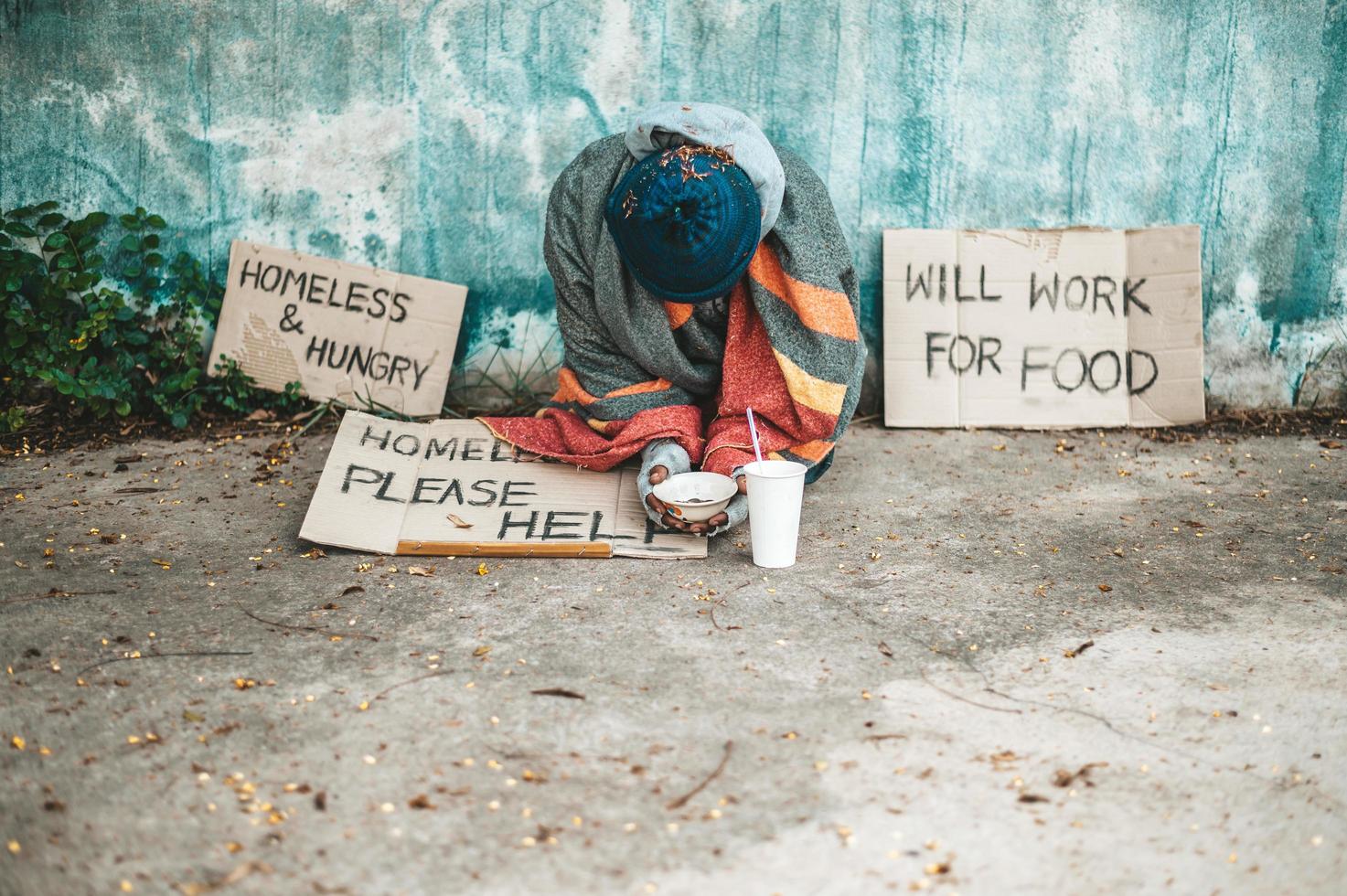 man zit naast de straat met een daklozenbericht foto