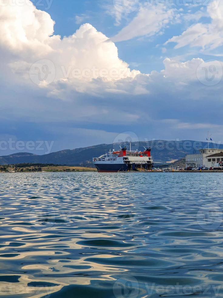 groot wit schip. veerboot voor passagiers en voertuigen. auto's laden en mensen instappen op het schip in de haven van volos, griekenland. foto