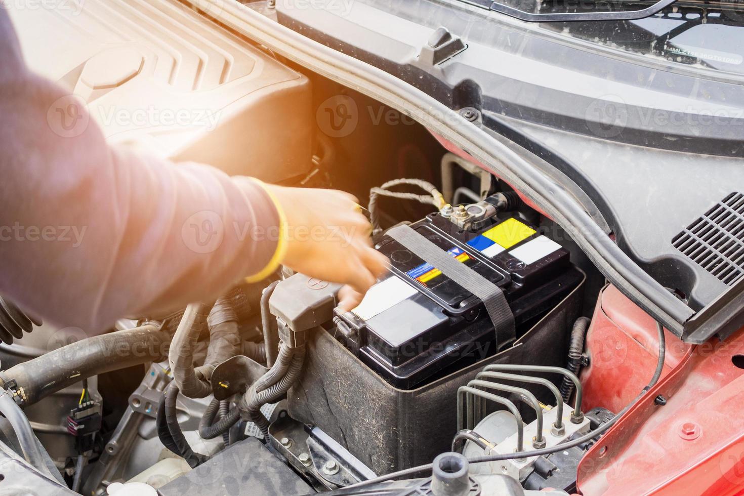 automonteur gebruik voltmeter om het spanningsniveau van de auto-accu te controleren; foto