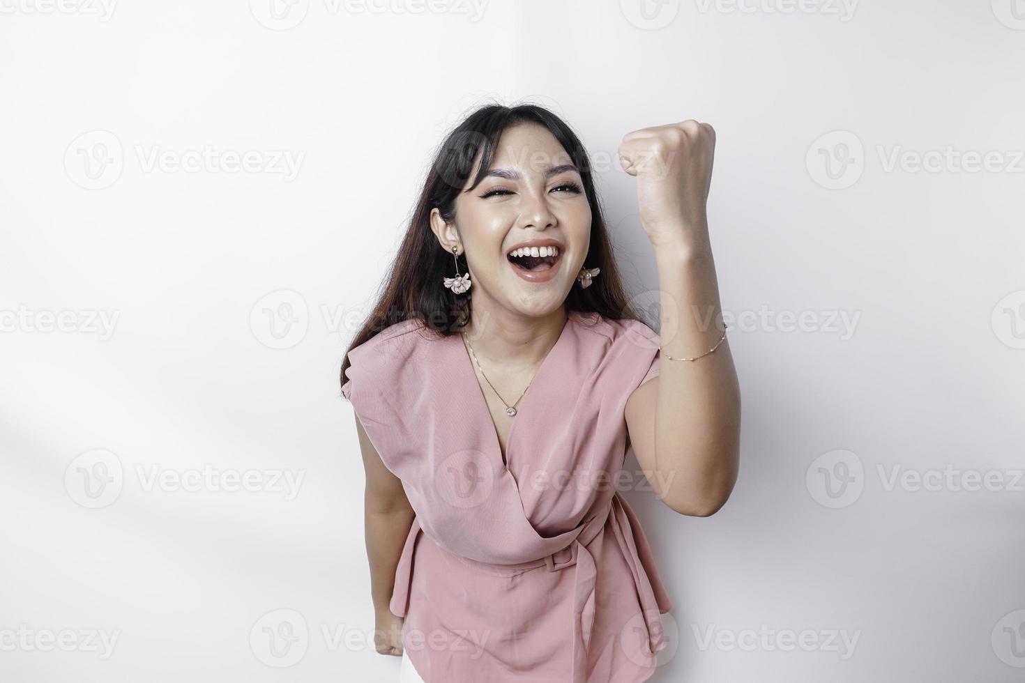 een jong Aziatisch vrouw met een gelukkig geslaagd uitdrukking vervelend roze blouse geïsoleerd door wit achtergrond foto