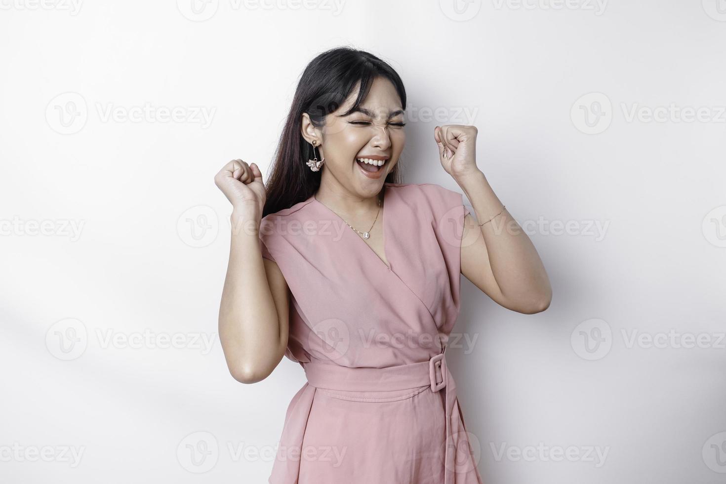 een jong Aziatisch vrouw met een gelukkig geslaagd uitdrukking vervelend roze blouse geïsoleerd door wit achtergrond foto