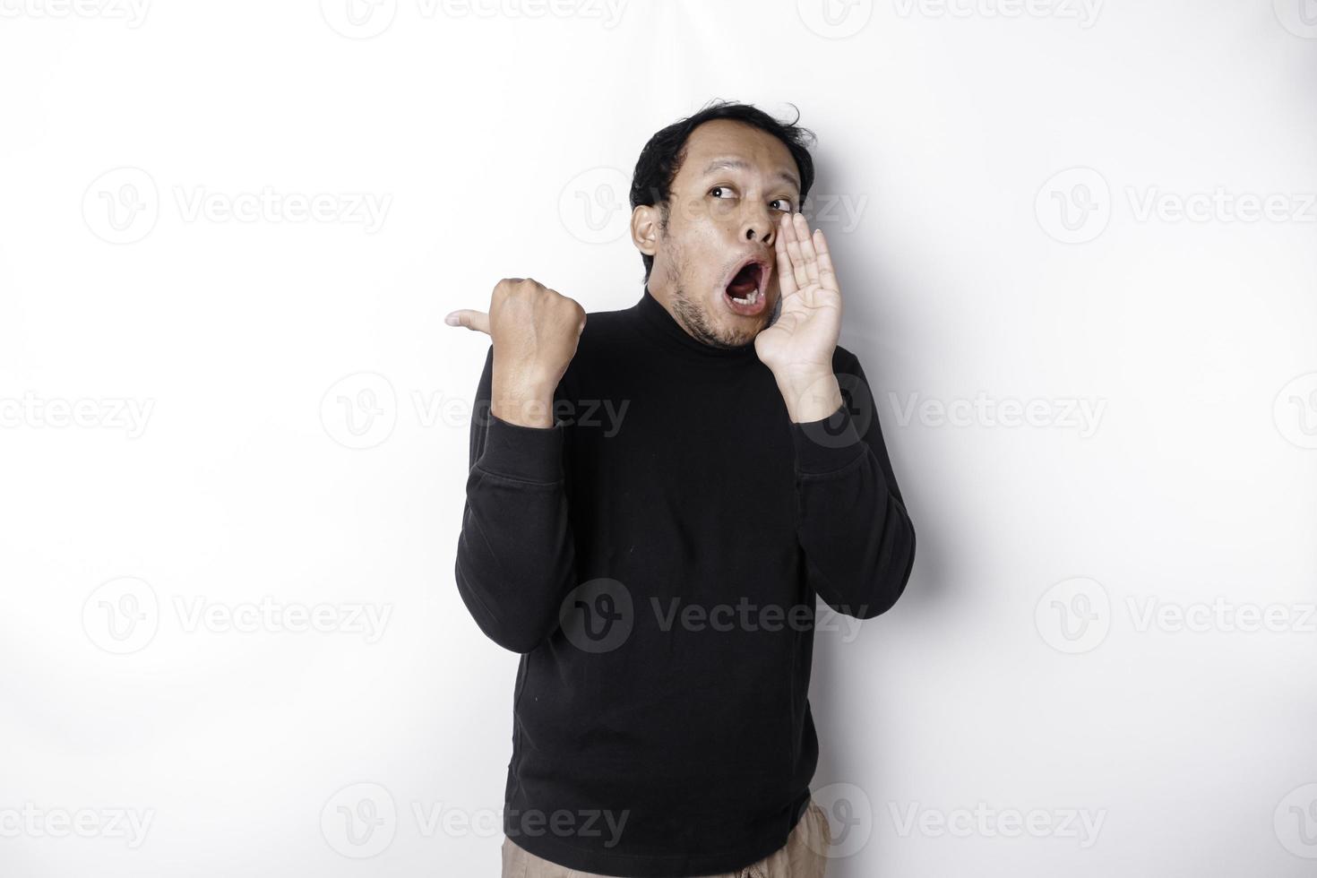 geschokt Aziatisch Mens vervelend zwart overhemd richten Bij de kopiëren ruimte naast hem, geïsoleerd door wit achtergrond foto