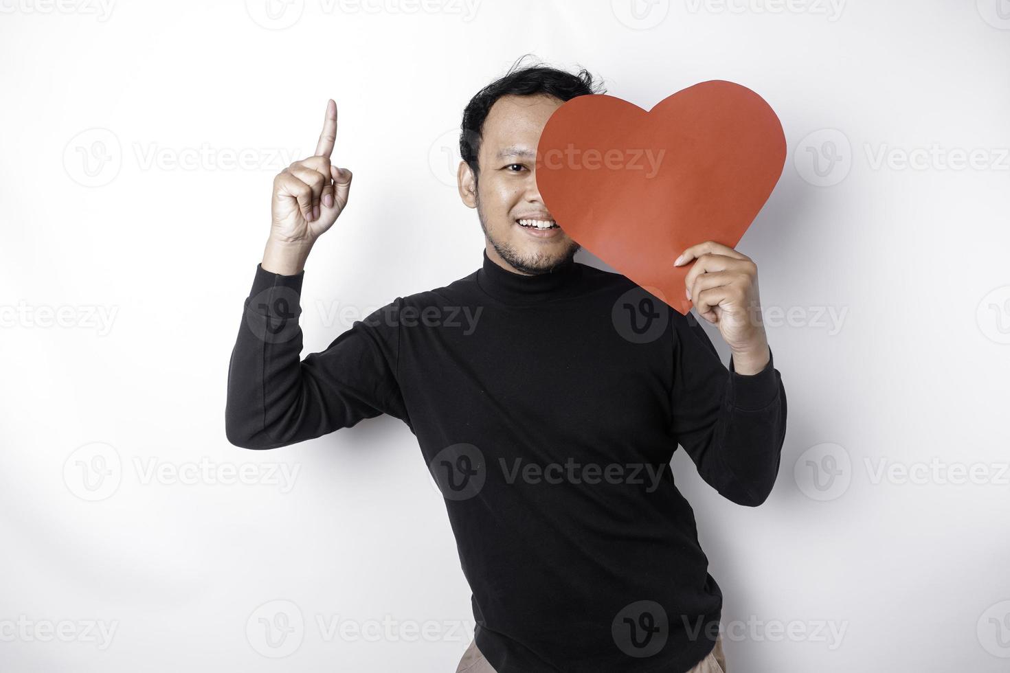 portret van een glimlachen Aziatisch Mens Holding een groot rood hart symbool richten omhoog Bij kopiëren ruimte geïsoleerd over- wit achtergrond foto