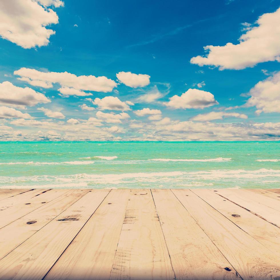 strand zee en blauw lucht wolken met hout tafel, wijnoogst toon. foto