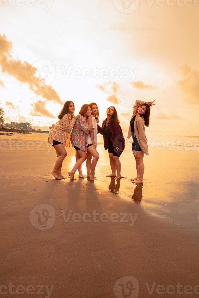 een groep van Aziatisch Dames in overhemden poseren gelukkig terwijl bezoekende een mooi strand foto