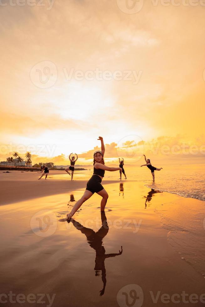 een groep van Aziatisch Dames in zwart kleren spelen met hun vrienden Aan de strand foto