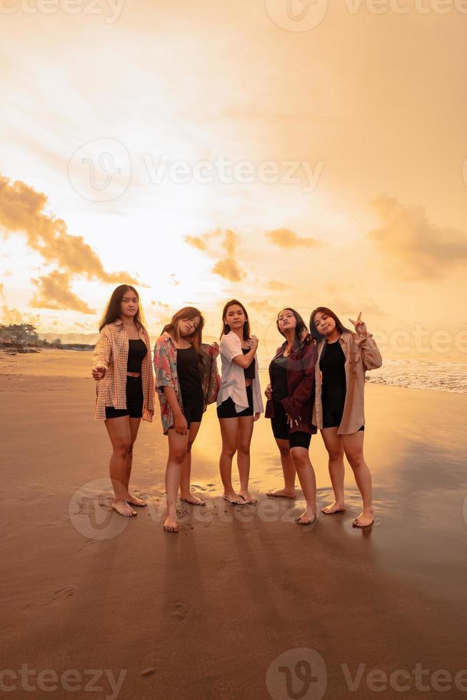 een groep van Aziatisch Dames in overhemden poseren gelukkig terwijl bezoekende een mooi strand foto