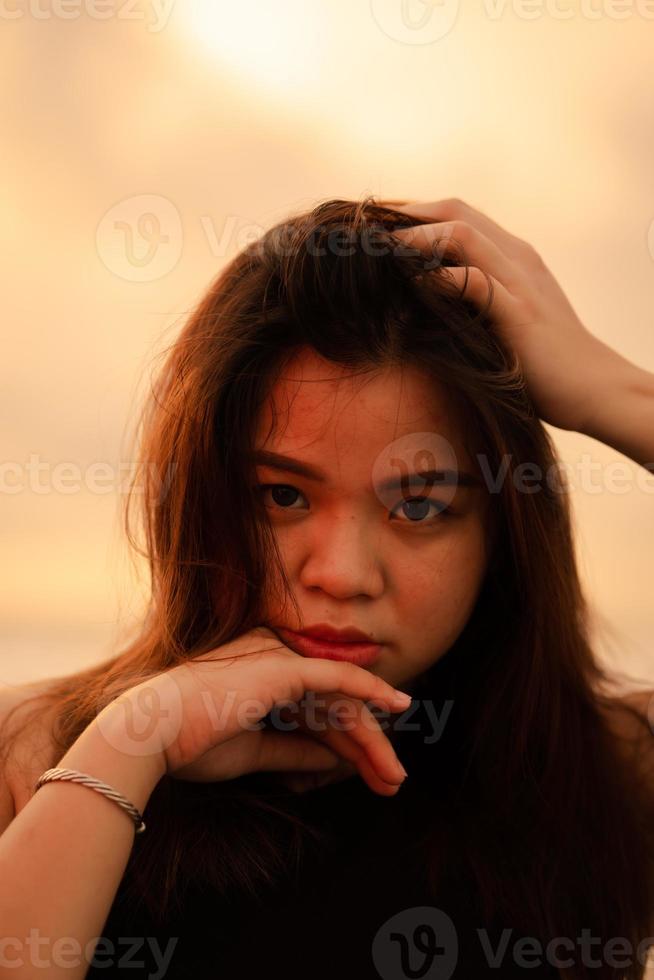 een Aziatisch vrouw met blond haar- is poseren door Holding haar hoofd Aan de strand foto