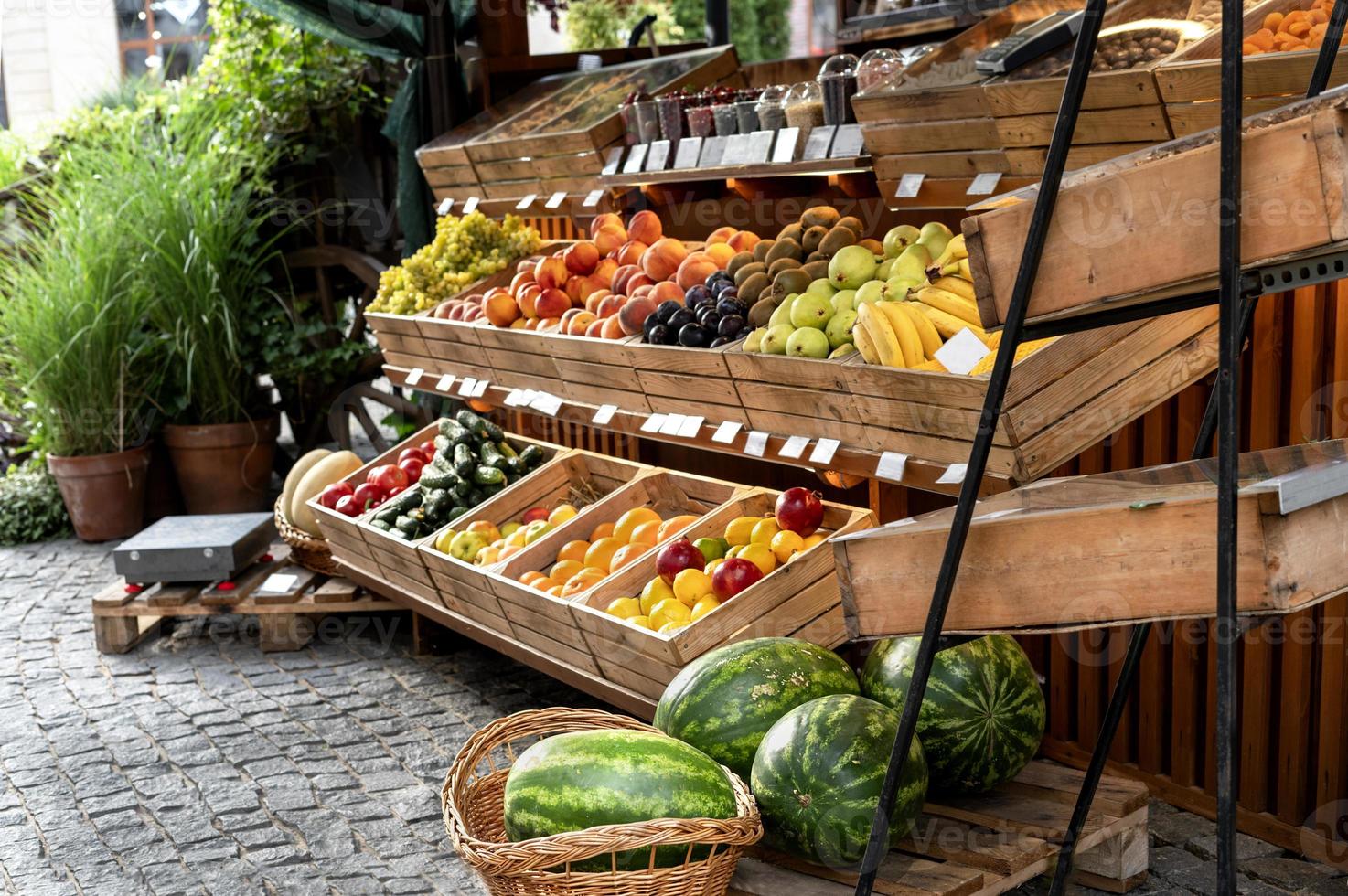 fruit staan Bij een straat markt buiten met biologisch watermeloenen, sinaasappelen, citroenen in houten kratten klein bedrijf veganistisch gezond voedsel foto