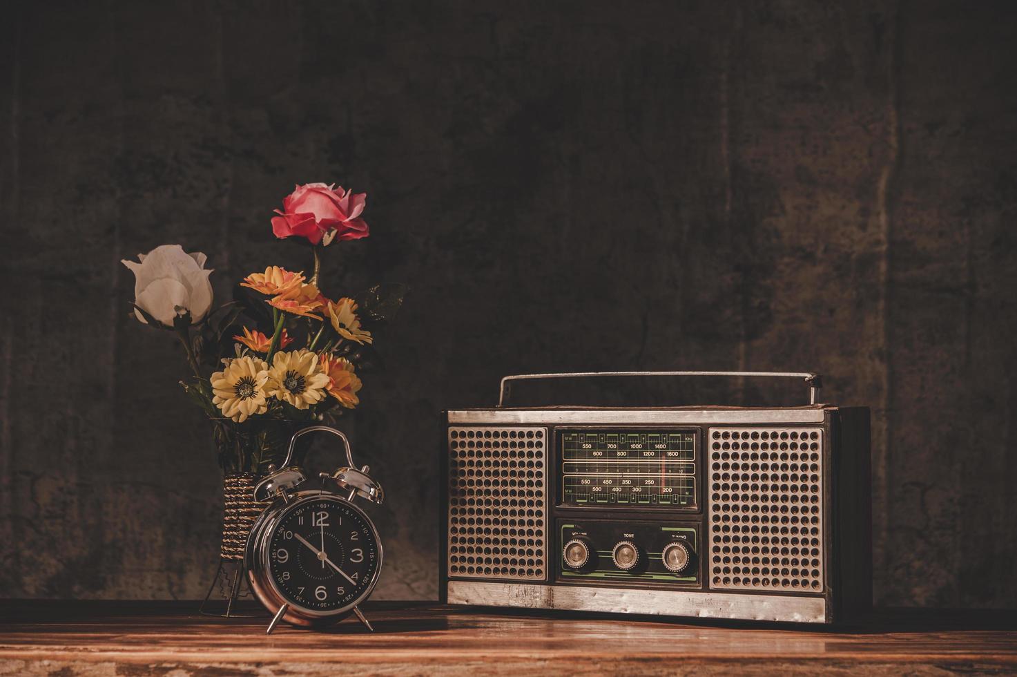 retro radio-ontvanger stilleven met klokken en bloemenvazen foto