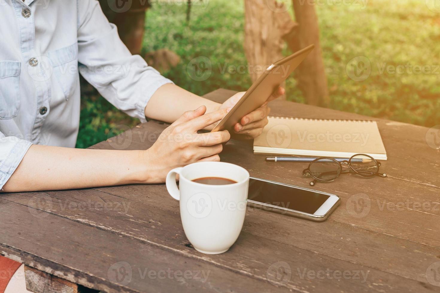 Aziatisch vrouw gebruik makend van tablet in tuin Bij koffie winkel met wijnoogst toon. foto