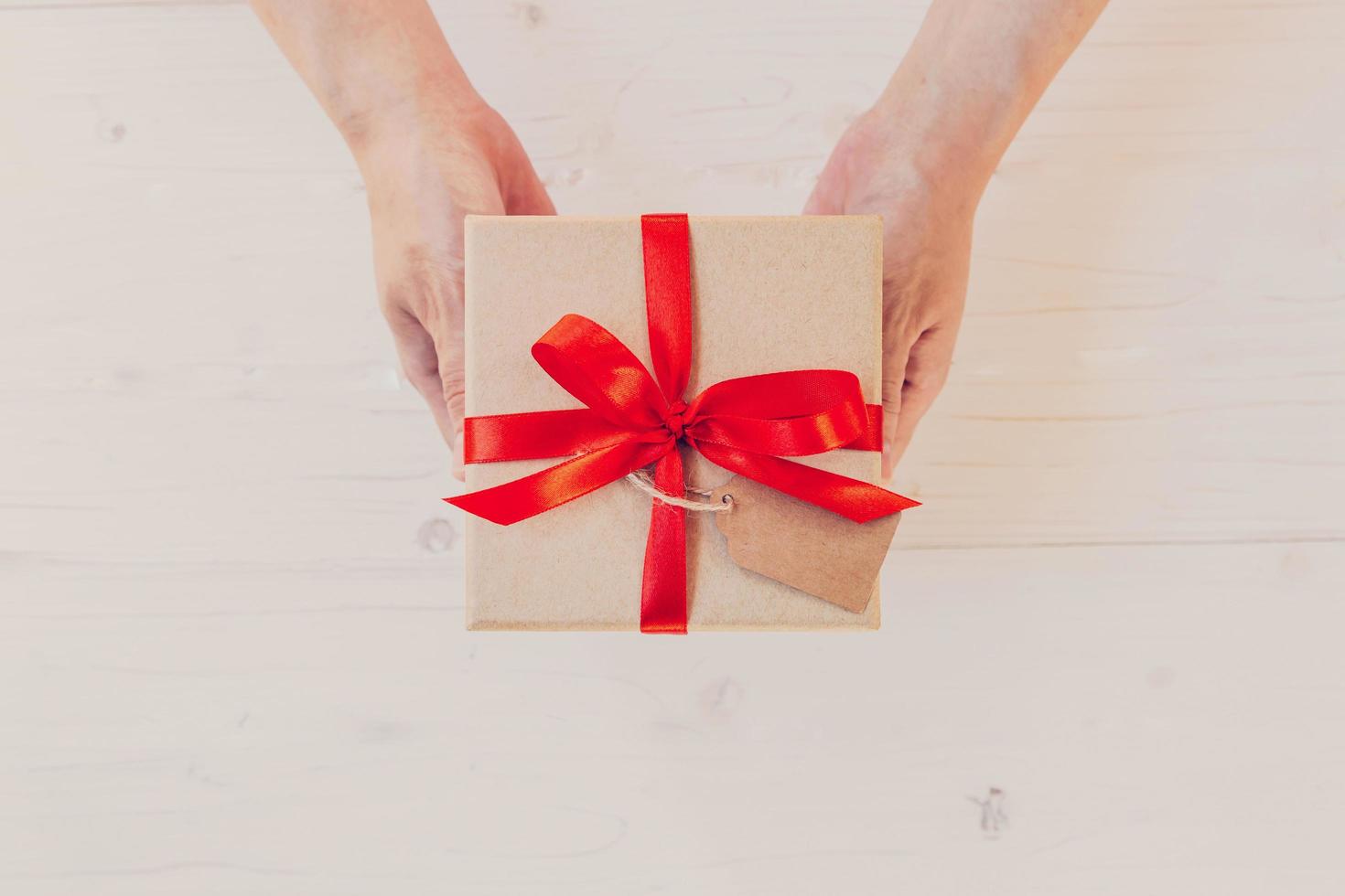 top visie hand- vrouw Holding bruin geschenk doos Aan wit hout achtergrond. foto