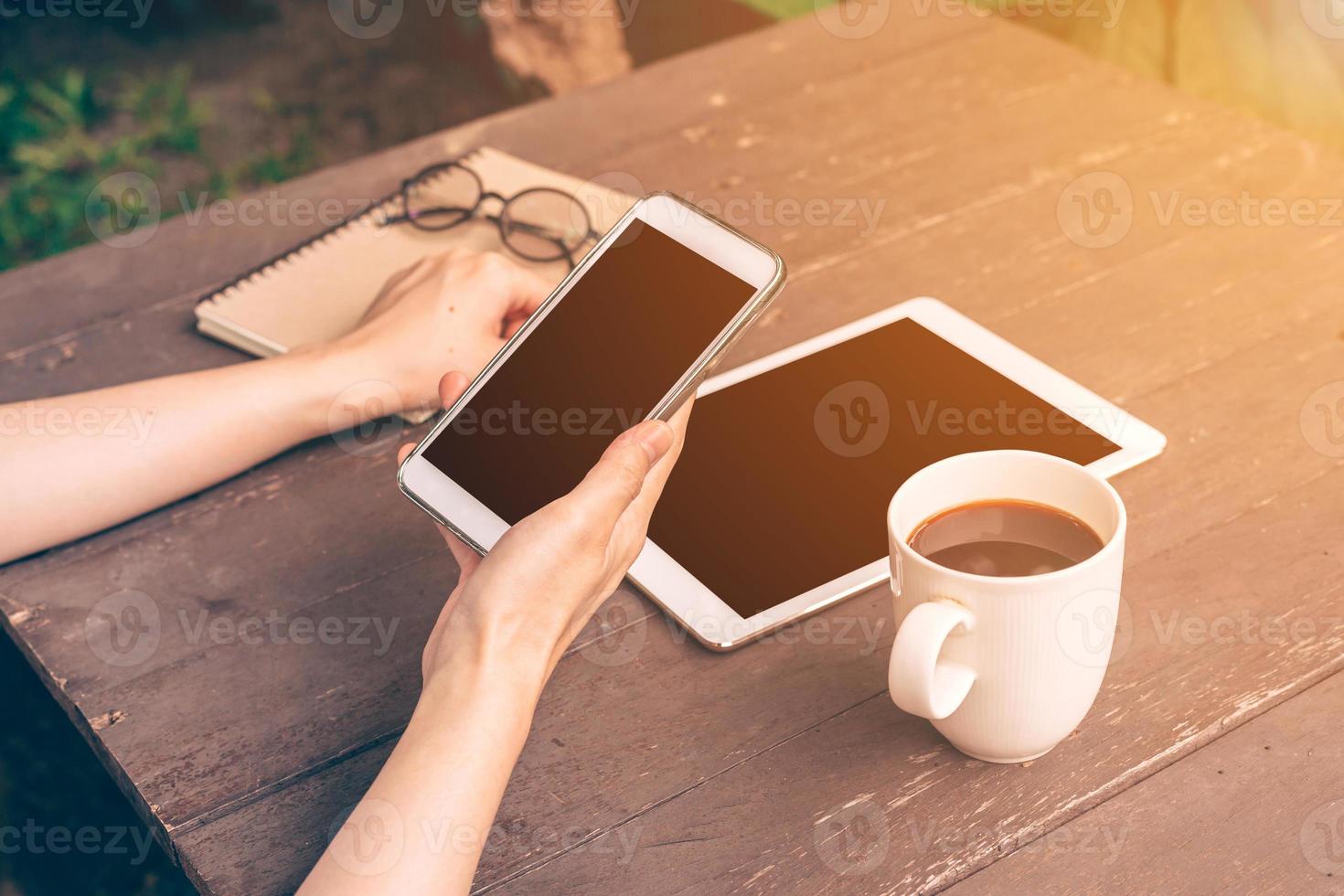 dichtbij omhoog hand- Azië vrouw gebruik makend van telefoon in koffie winkel met wijnoogst filter. foto