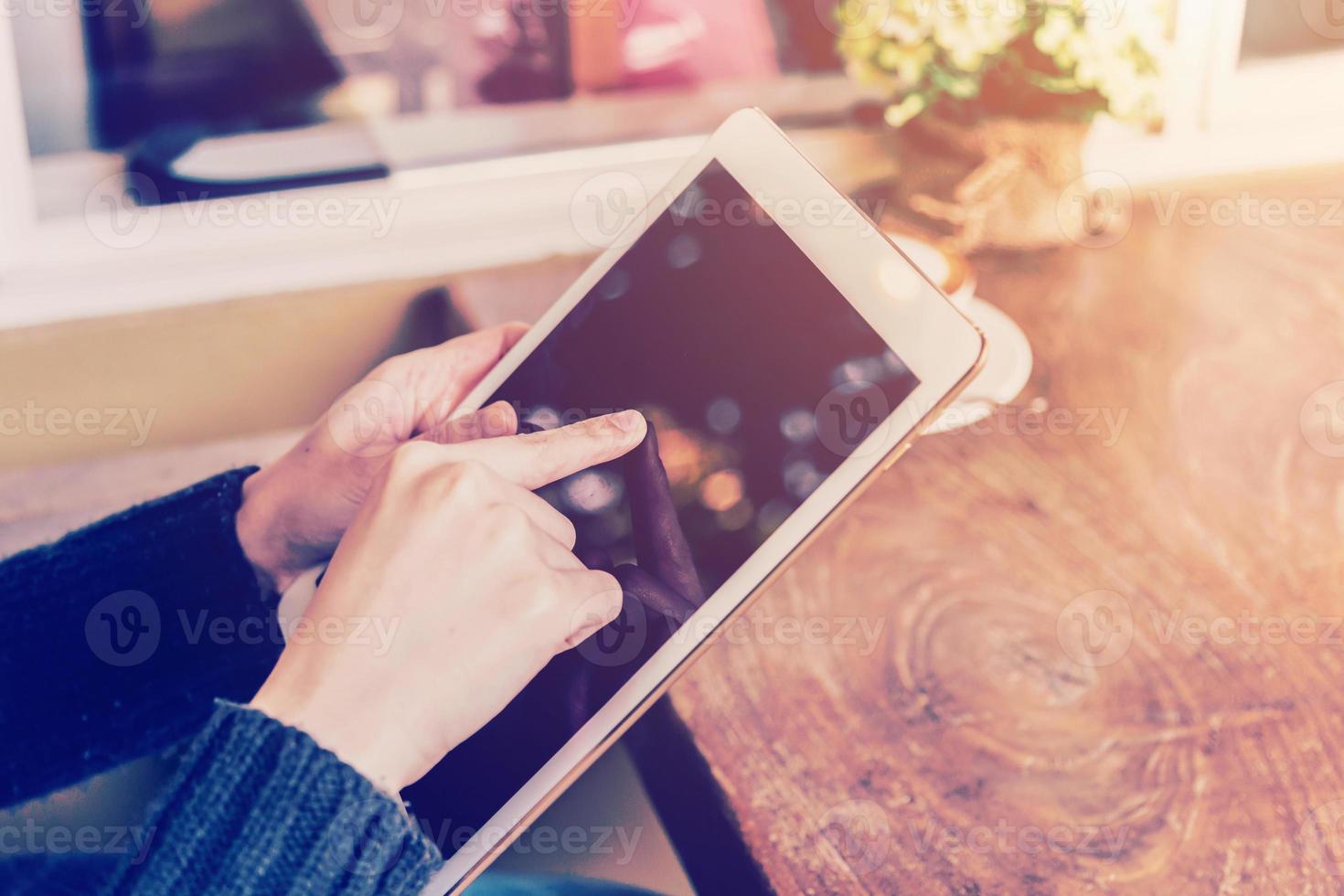 Aziatisch vrouw hand- Holding tablet en gebruik makend van tablet in koffie winkel met wijnoogst afgezwakt. foto