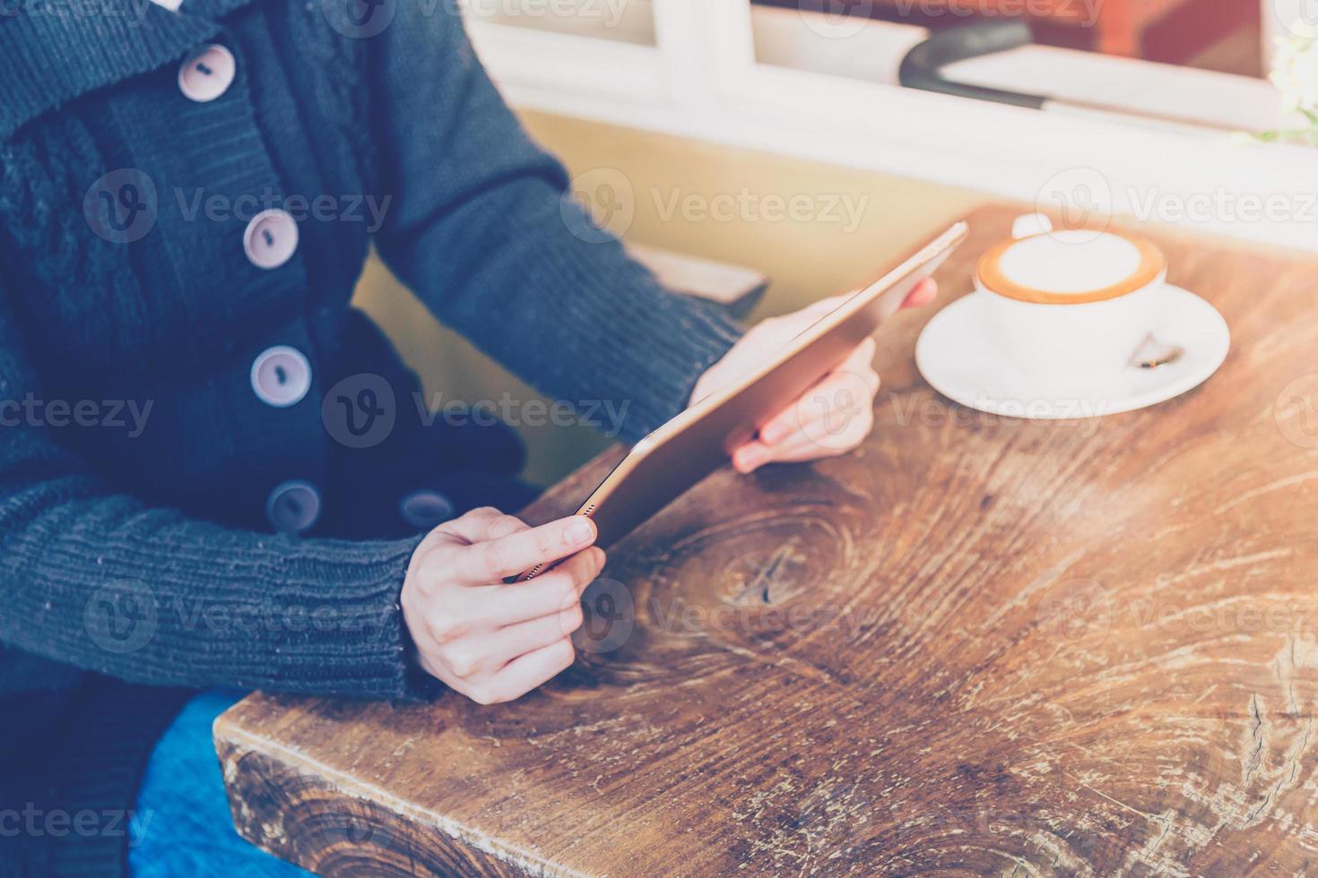 vrouw gebruik makend van tablet en diepte van veld- in koffie winkel met wijnoogst toon. foto