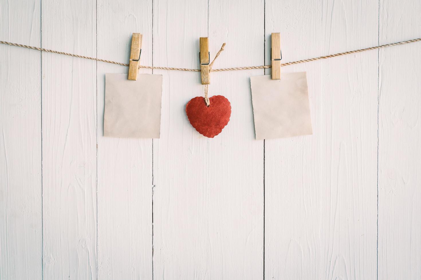 twee blanco oud papier en rood hart hangen. Aan wit houten achtergrond met wijnoogst stijl. foto