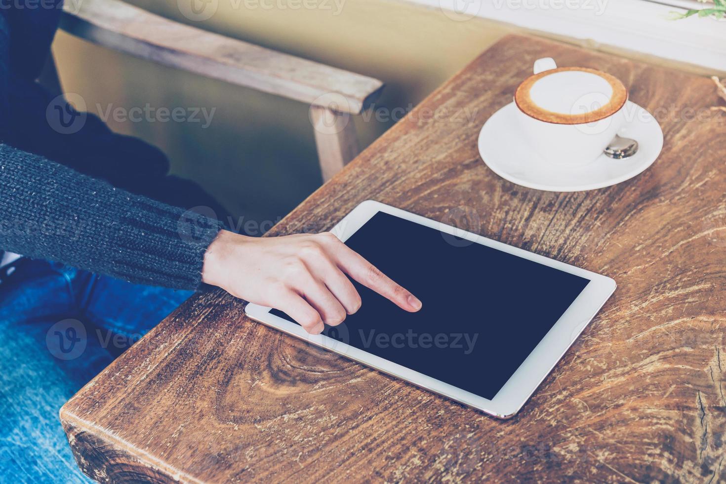 vrouw gebruik makend van tablet in koffie winkel met wijnoogst toon. foto