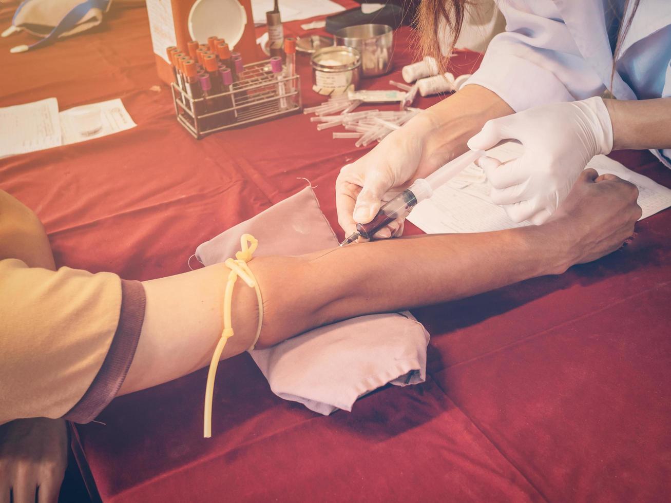 dichtbij omhoog hand- Mens en verpleegster nemen een bloed monster met wijnoogst filter. foto