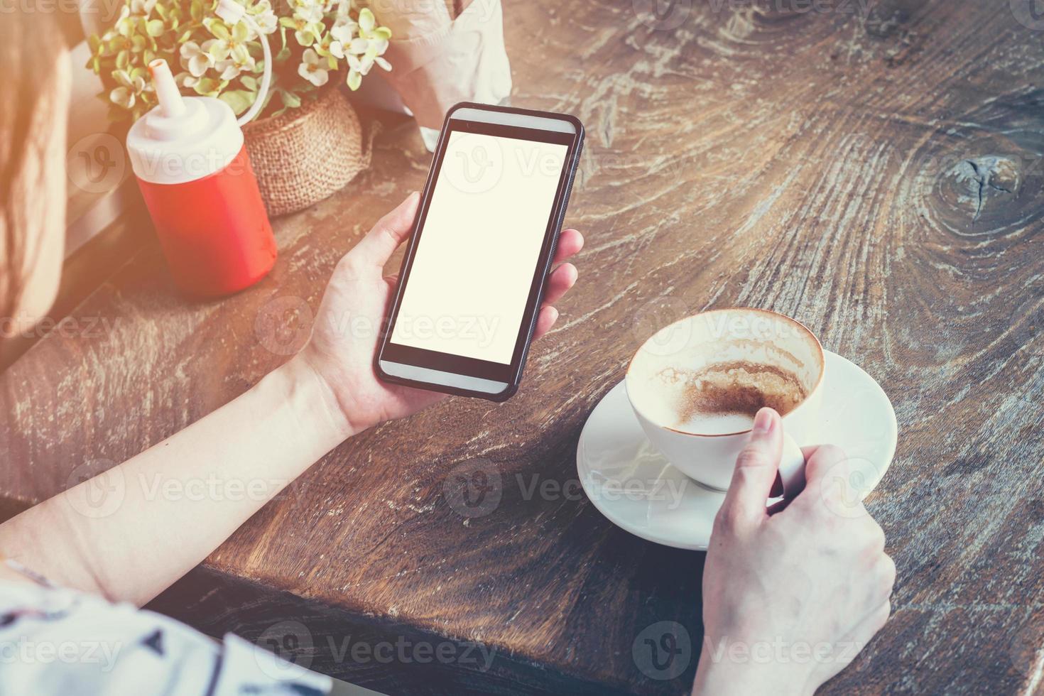 dichtbij omhoog van hand- vrouw gebruik makend van telefoon in koffie winkel met wijnoogst afgezwakt. foto