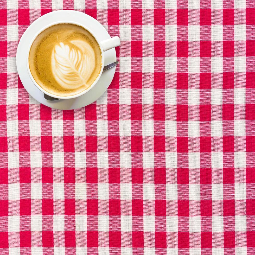 cappuccino koffie Aan wit en rood geruit achtergrond dichtbij omhoog foto