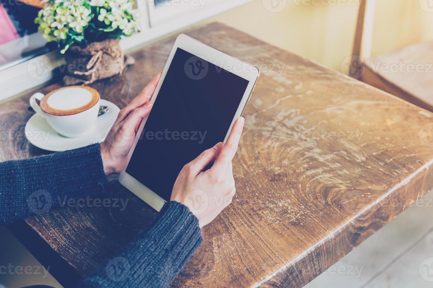 vrouw gebruik makend van tablet in koffie winkel met wijnoogst toon. foto