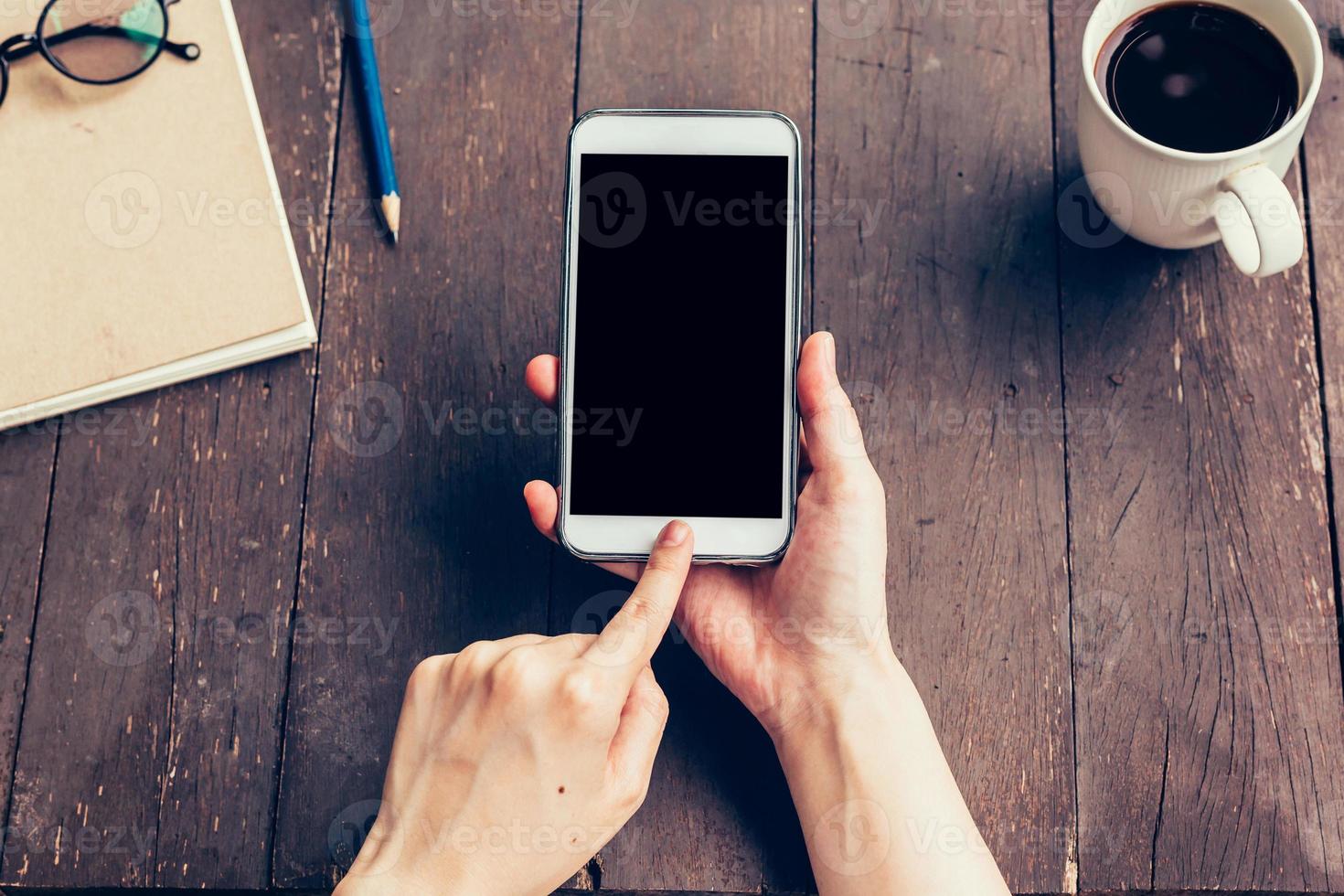 dichtbij omhoog van vrouw hand- Holding telefoon met blanco kopiëren ruimte scherm voor uw reclame. hand- vrouw gebruik makend van telefoon in koffie winkel. foto