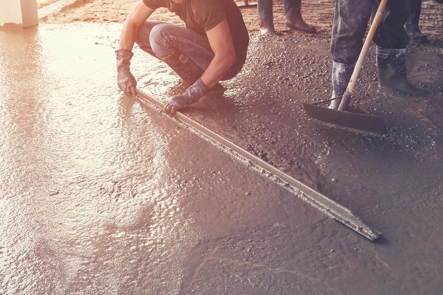 Mens stukadoor dekvloer beton Aan cement voor verdieping in gebouw bouw met wijnoogst afgezwakt. foto