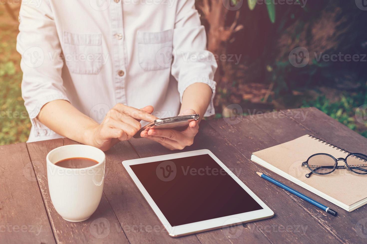 dichtbij omhoog hand- Holding en gebruik makend van telefoon in koffie winkel met wijnoogst afgezwakt. foto