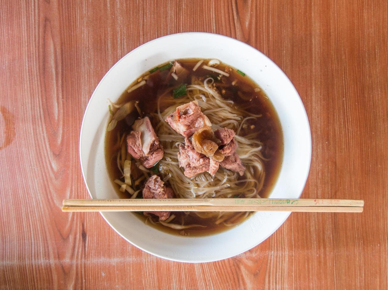 Thais noodle soep met vlees Aan hout tafel foto