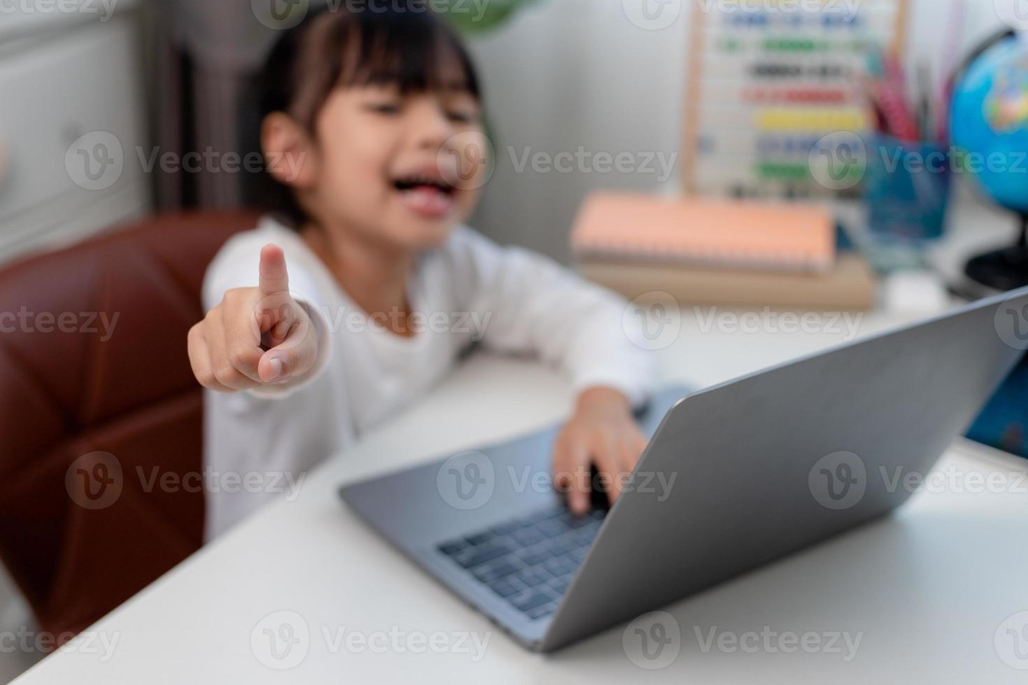 Aziatisch schoolmeisje aan het doen haar huiswerk met laptop Bij huis. kinderen gebruik gadgets naar studie. onderwijs en afstand aan het leren voor kinderen. thuisonderwijs gedurende quarantaine. blijven Bij huis foto