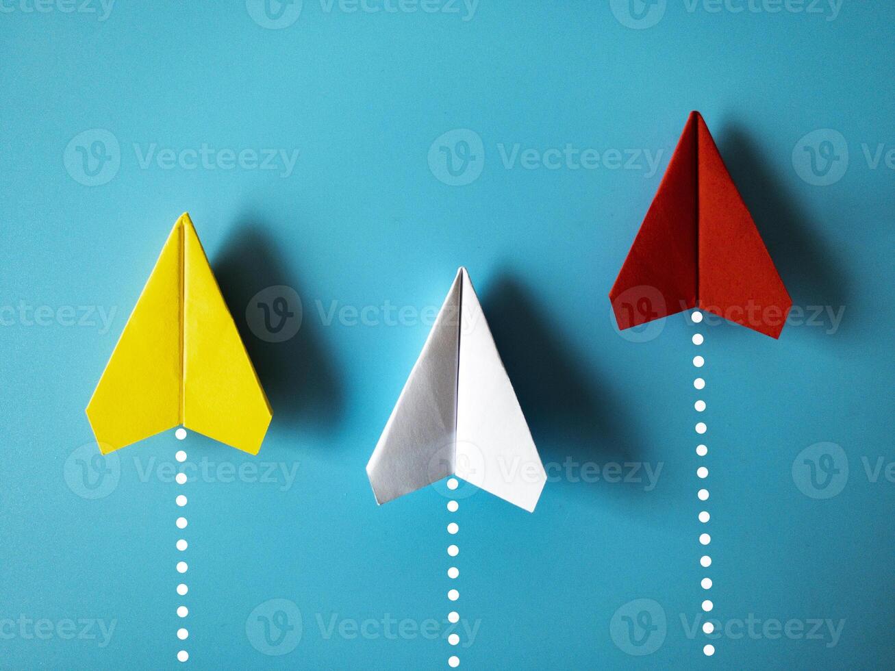 geel, wit en rood papier vliegtuig origami racing naar bereiken bestemming Aan blauw achtergrond met aanpasbare ruimte voor tekst. bedrijf doelen concept foto
