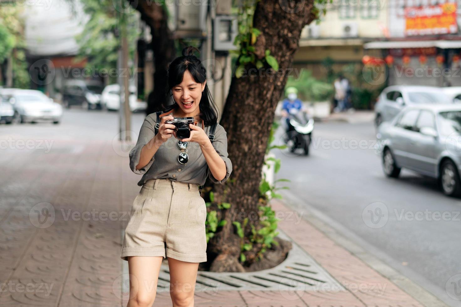 jong Aziatisch vrouw rugzak reiziger gebruik makend van digitaal compact camera, genieten van straat cultureel lokaal plaats en glimlach. foto