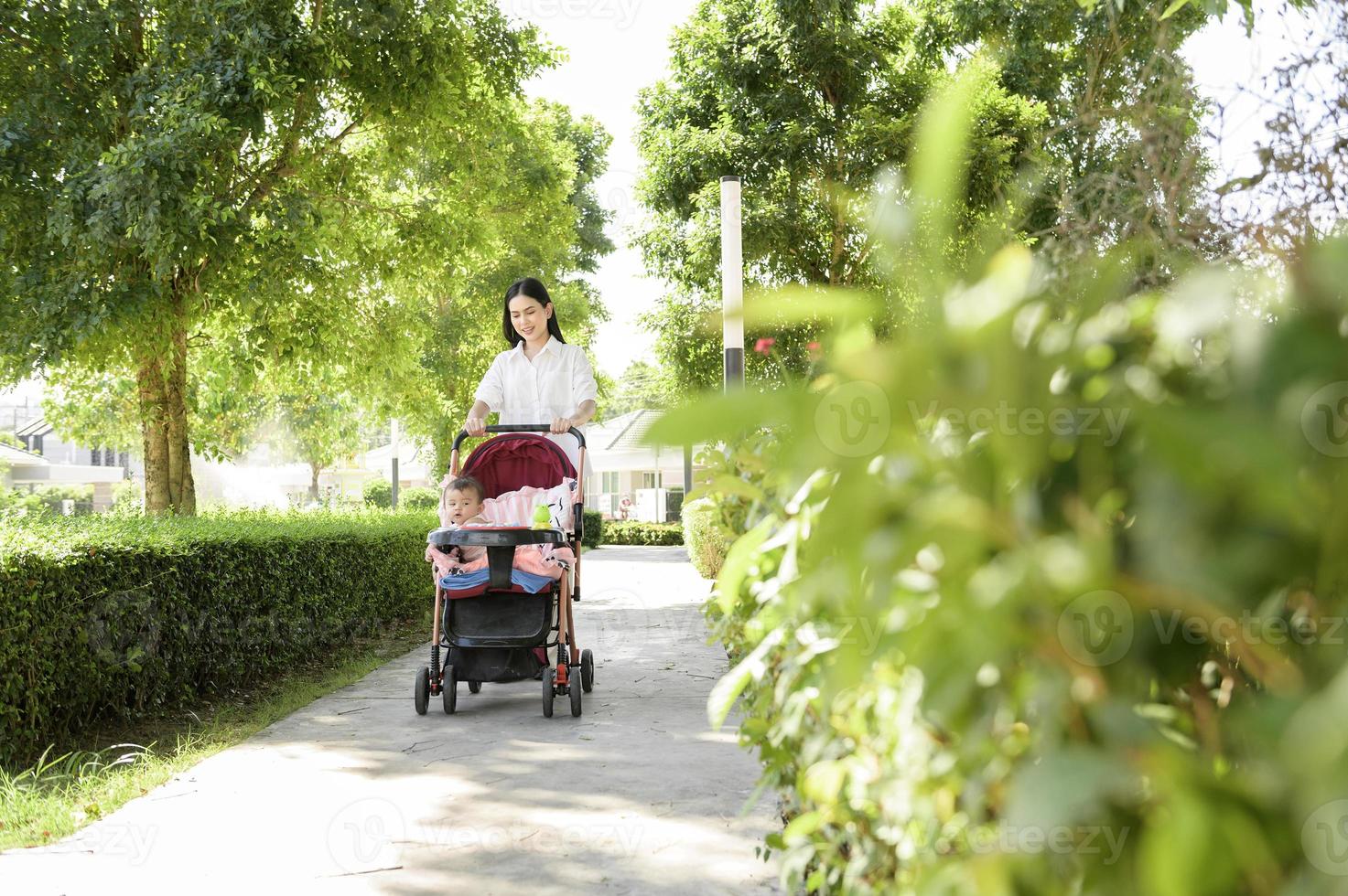 mooi mam met een baby meisje zittend Aan baby trolley buitenshuis in zonneschijn dag foto