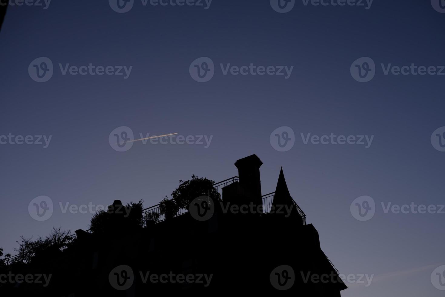 silhouet wijnoogst huizen met vliegtuig rook in zonsondergang lucht. foto