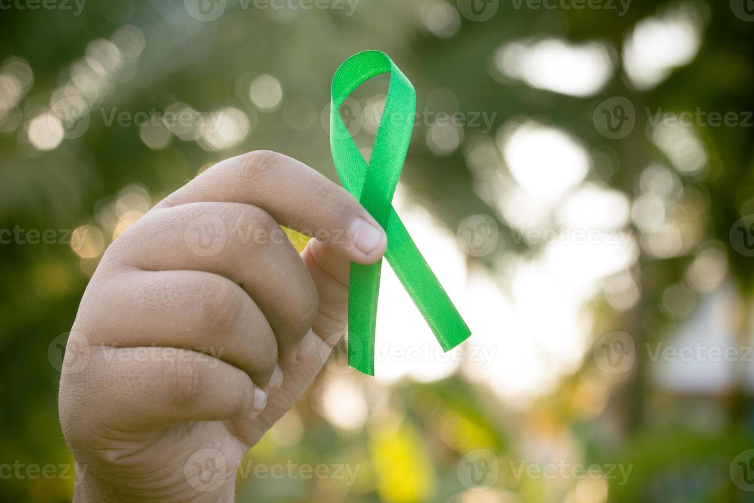hand- Holding een groen lintje. kanker behandeling concept. foto