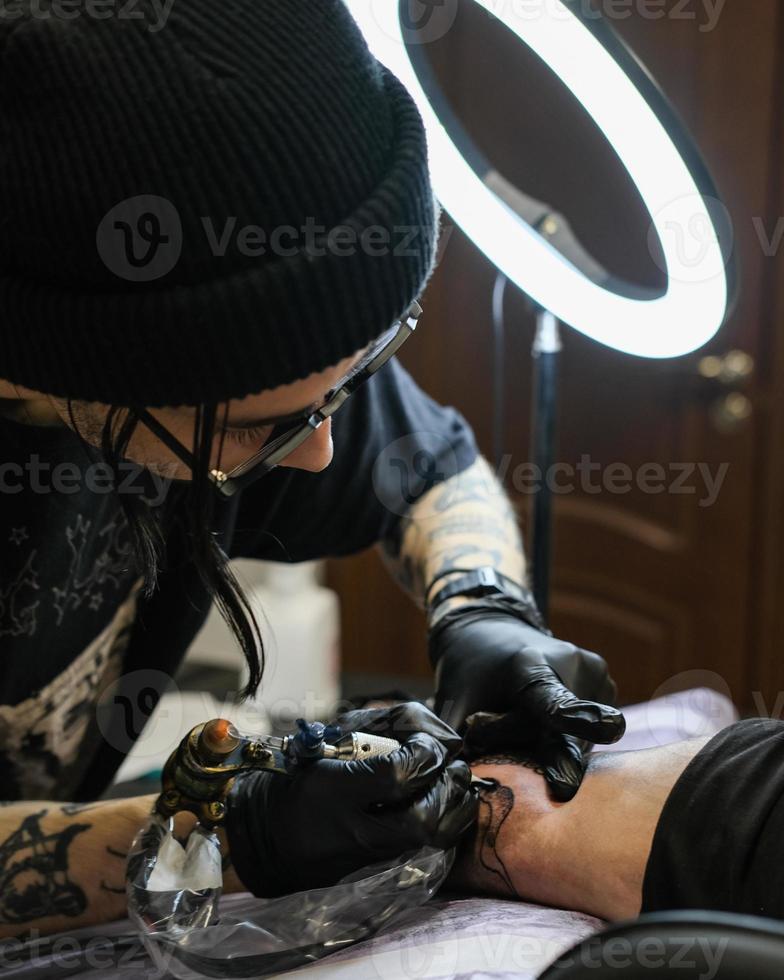 professioneel tatoeëren artiest spullen een tatoeëren Aan de man's hand. tatoeëren artiest Bij werk. tatoeëren creatie werkwijze. kunst en creativiteit foto