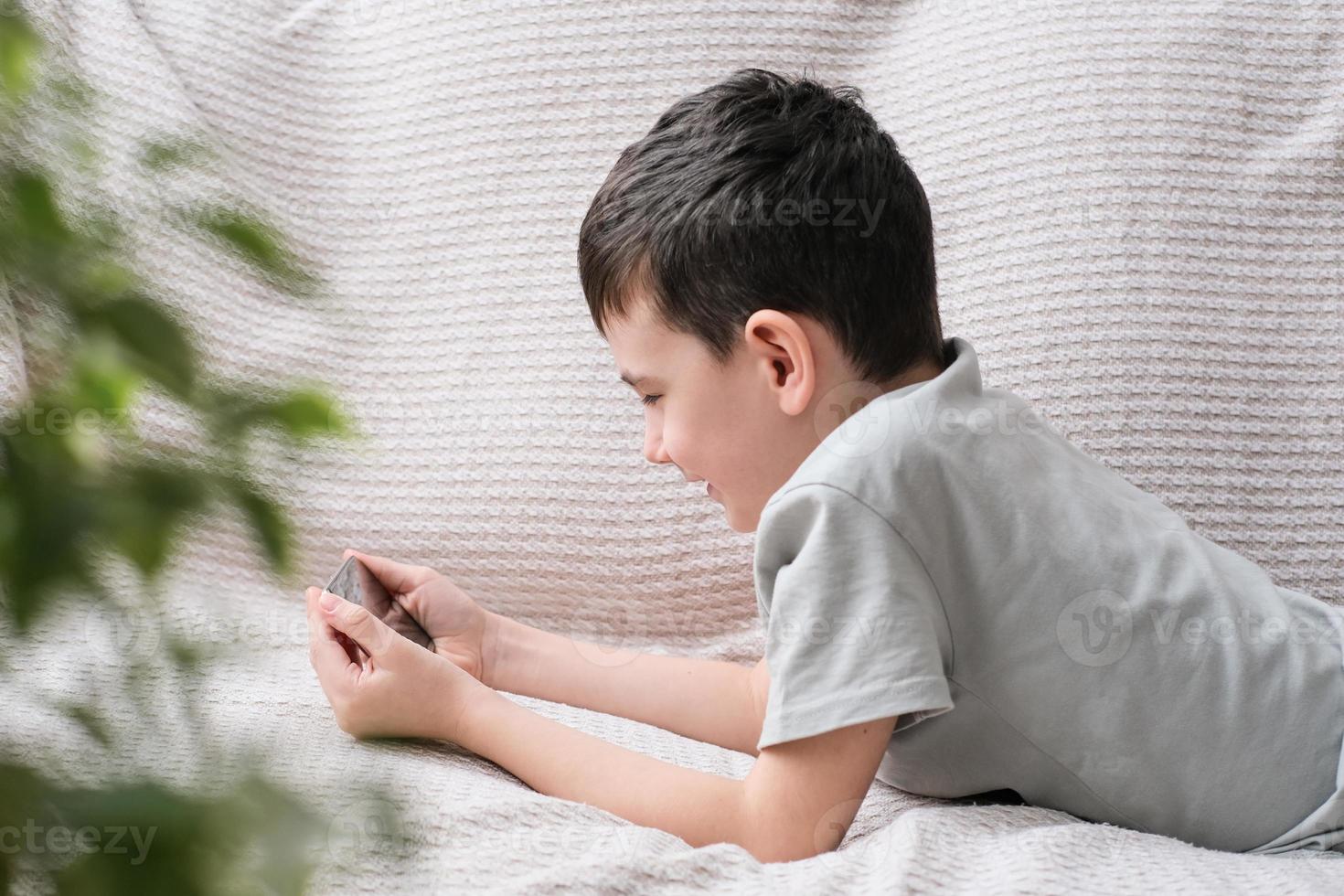 jongen aan het kijken video Aan telefoon en lachend foto